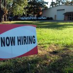 a now hiring sign in front of a building